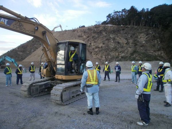 建設現場で重機の前に立つ作業員と安全確認の様子